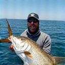 Ravi Kumar proudly holding a trophy-sized fish on an AquaGlimmer charter